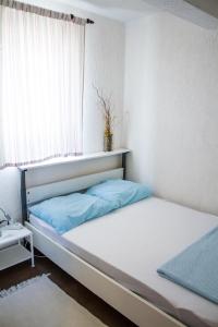 a bed with blue pillows in a room with a window at Apartments "I & I" in Pag