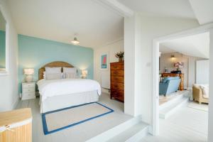 a bedroom with a white bed and a blue wall at Penrose in Downderry