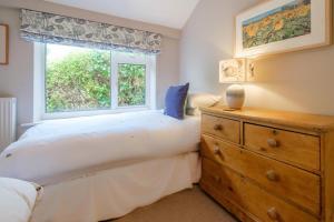 a bedroom with a bed and a window and a dresser at Penrose in Downderry