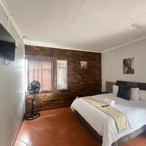 a bedroom with a bed and a brick wall at MBT Lodge in Polokwane +51 photos