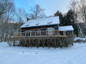 a log cabin with a snow covered roof in the snow at Ayers Farm Cottage in Stowe