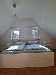 a bed in a room with two windows at Haus am Ponyhof in Aurich