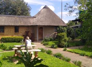 a woman sitting on a bench in front of a building at Rangers Airport Lodge in Benoni