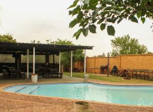 a swimming pool with a pavilion and a picnic table at Rangers Airport Lodge in Benoni