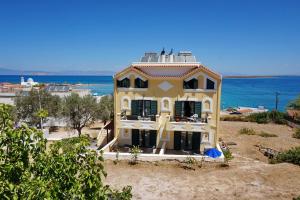 una grande casa gialla con l'oceano sullo sfondo di Vasilaras Hotel a Skala