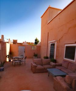a patio with a couch and a table on a building at Dar INNÂ in Aït Benhaddou