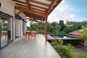 Un patio con mesa y sillas y una piscina. en Villa Indonésie-piscine privé au centre de l'île, en Les Abymes