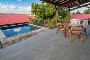 Un patio con mesa y sillas y una piscina. en Villa Indonésie-piscine privé au centre de l'île, en Les Abymes 3 fotos más