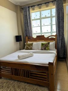 a bedroom with a large wooden bed with a window at Lovely 2-bedroom Fully-Furnished apartment in Nanyuki +6 photos