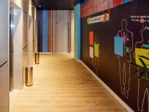 a hallway with a wooden floor and a wall with paintings at ibis budget Maceió Pajuçara in Maceió