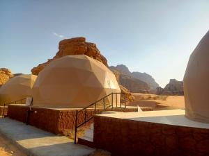 a row of domes in the desert with mountains at Wadi Rum Marcanã camp in Aqaba