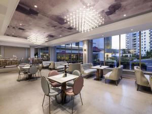 a restaurant with tables and chairs and large windows at Mercure Qingdao Downtown in Qingdao