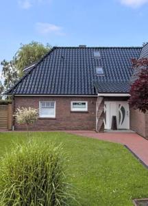 a brick house with a black roof and a yard at Ferienwohnung Blinkfüer in Hinte