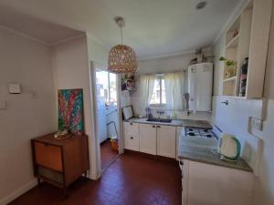 ArgentinaにあるDepto para 4 en Barrio Chauvínの白いキャビネット、シンク、冷蔵庫付きのキッチンが備わります。