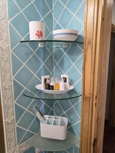a bathroom with a blue tiled wall with shelves at Casetta Ladunia in Porto Rotondo