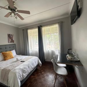 a bedroom with a bed and a table and a chair at MBT Lodge in Polokwane