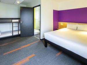 Un dormitorio con una cama grande y una pared morada. en greet Hotel Nancy Sud, en Houdemont 61 fotos más