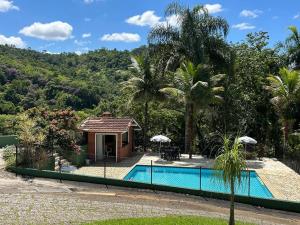 a swimming pool with a gazebo and a house at Casa em Penedo - Itatiaia in Itatiaia