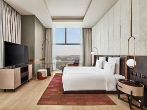 a bedroom with a large white bed and a large window at Swissôtel Clark Philippines in Clark +94 photos