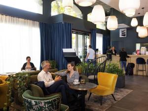 a man and woman sitting on couches in a lobby at Aparthotel Adagio Lyon Patio Confluence in Lyon