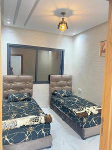 two twin beds in a room with a ceiling at Real appartement in El Jadida