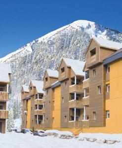 a group of buildings in front of a snow covered mountain at Appartement F2 au domaine des 100 lacs - piscine - sauna - hammam in Cauterets