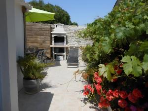 a patio with a grill and some plants and flowers at La venelle des Ormeaux in Les Moulins de la Boire