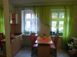 a kitchen with a table and two windows with green curtains at Hostel CION in Gliwice