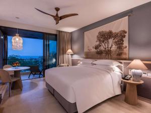 Un dormitorio con una gran cama blanca y un comedor. en Sofitel Barú Cartagena, en Cartagena de Indias
