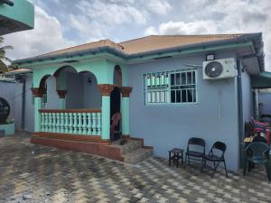 une maison bleue avec deux chaises devant dans l'établissement Cozy Flat 5 Minutes To Beach, à Freetown