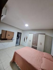 a bedroom with a pink bed and a kitchen at Casa completa Petrolina-PE in Petrolina