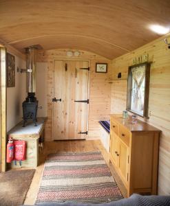 a small room with a stove in a log cabin at Honeysuckle Shepherds Hut at Blean Bees Eco Glamping in Canterbury