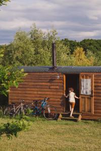 a young girl standing outside of a wooden cabin at Honeysuckle Shepherds Hut at Blean Bees Eco Glamping in Canterbury