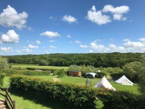 a view of a field with tents and trees at Honeysuckle Shepherds Hut at Blean Bees Eco Glamping in Canterbury