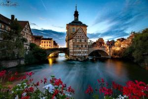 a building with a clock tower next to a river at FeWo Viktoria in Bamberg