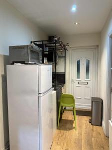 a kitchen with a refrigerator and a green chair at Stylish Self Contained Unit - High Wycombe in High Wycombe