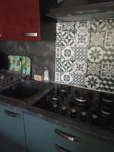 a kitchen with a sink and a tile wall at L'Amazone in Saint-Maurice-de-Beynost