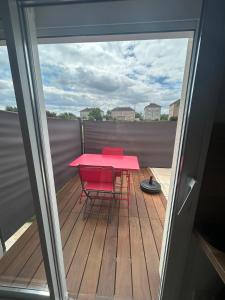 una mesa roja y dos sillas rojas en una terraza en Studio Confort à Lapalisse, en Lapalisse