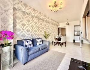 Una sala de estar con un sofá azul y un comedor. en Comfy Apt, Rooftop Lounge, Pool, en Ensanche Quisqueya