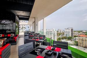 un restaurante con mesas y sillas y vistas a la ciudad en Comfy Apt, Rooftop Lounge, Pool, en Ensanche Quisqueya