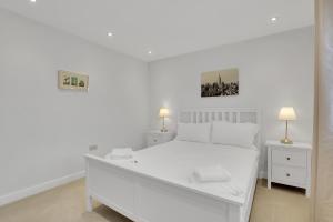 een witte slaapkamer met een wit bed en 2 lampen bij Sunrise View - North East Escapes in Long Houghton