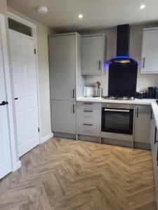 a kitchen with white cabinets and a wooden floor at The MacIntyre - Coorie Doon Stays in Kilmarnock +4 photos