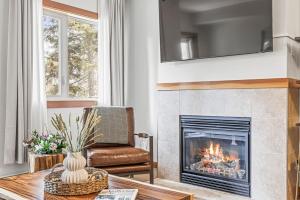 Una sala de estar con chimenea y una silla. en Chic 1BR City Nest Heated Parking and Hot Tub and Pool, en Canmore