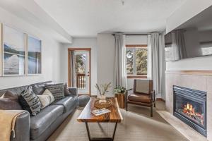 Una sala de estar con un sofá y una chimenea. en Chic 1BR City Nest Heated Parking and Hot Tub and Pool, en Canmore