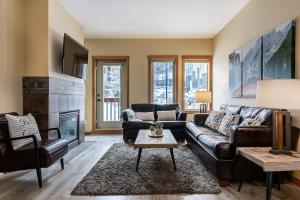 een woonkamer met een leren bank en een open haard bij 3BR Rockies Condo Heated Pool and Hot Tub in Canmore