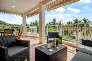 Un patio con sillas y mesas y vista al mar. en Appartement Alizés - Vue Mer et Accès plage direct, en Le Carbet