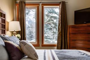 a bedroom with a bed and a window with snow at Spacious Getaway near Banff with Heated Pool in Canmore