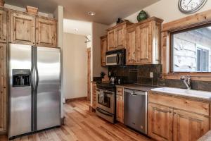 a kitchen with a stainless steel refrigerator and wooden cabinets at Twin Lift Lodge in Big Sky Mountain Village