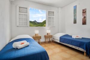 Dos camas en una habitación con ventana. en Appartement Alizés - Vue Mer et Accès plage direct, en Le Carbet