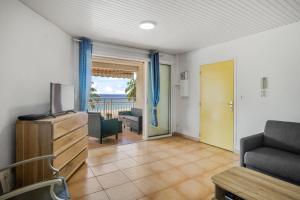 Una sala de estar con televisión y balcón. en Appartement Alizés - Vue Mer et Accès plage direct, en Le Carbet